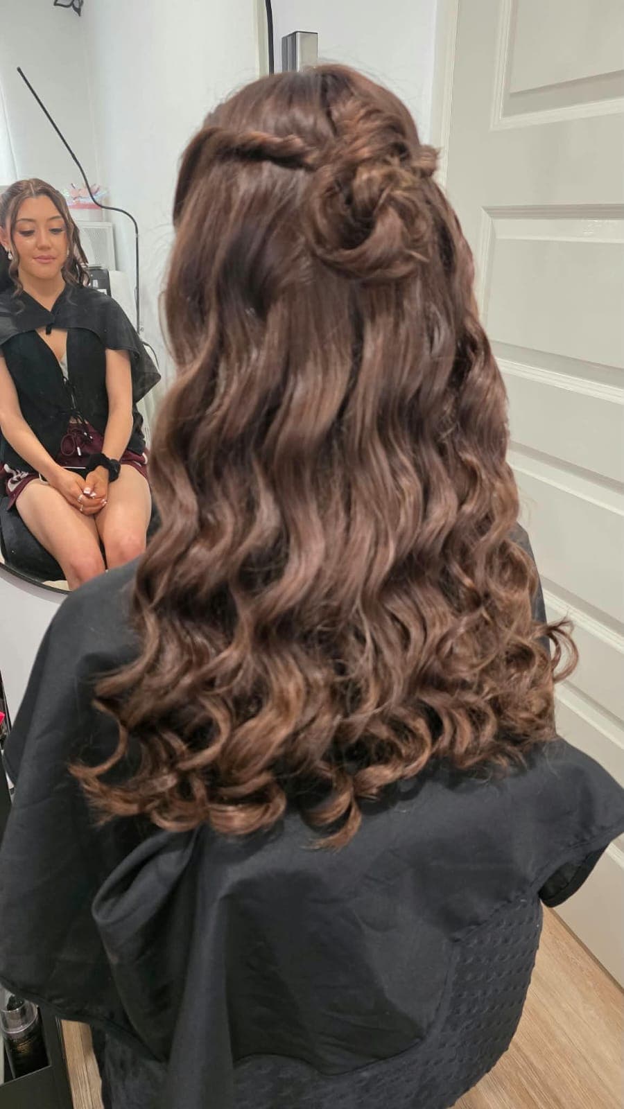 Hair styling detail from the back: long bouncy curls with a twisted half-up section
