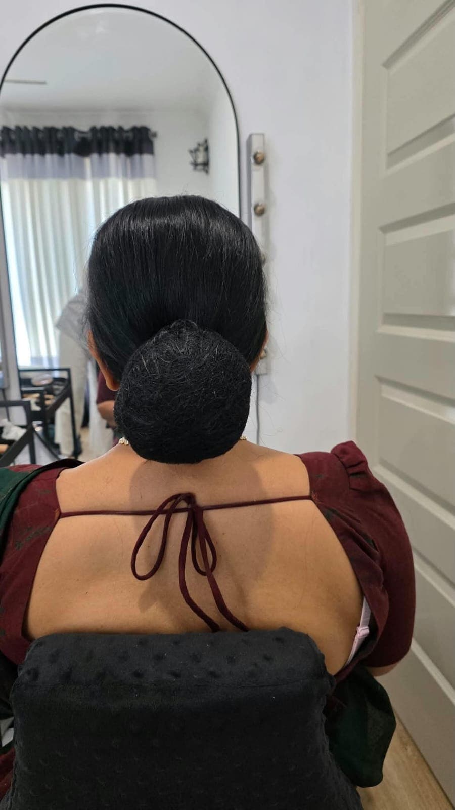 Hair styling detail from the back: a sleek, polished low bun for a traditional occasion